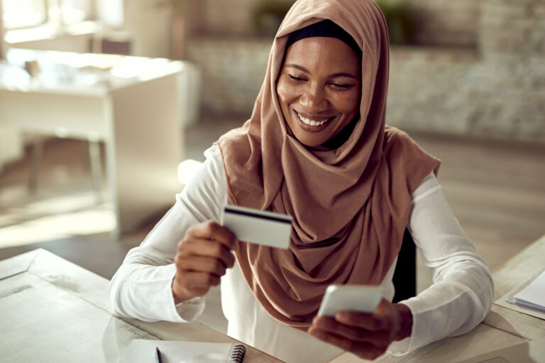 Happy Muslim businesswoman shopping online with credit card and